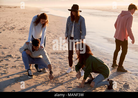 Friends Playing Noughts And Crosses In Sand On Winter Beach Stock Photo