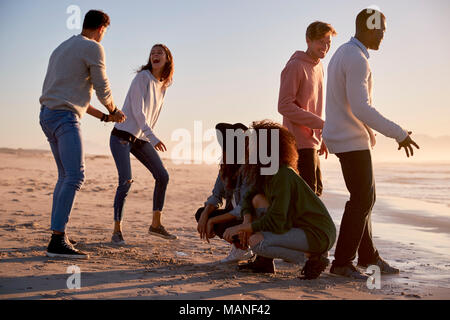 Friends Playing Noughts And Crosses In Sand On Winter Beach Stock Photo