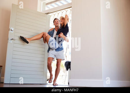 Man Carries Woman Over Threshold Of Honeymoon Rental Stock Photo