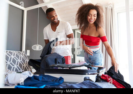 Couple In Bedroom Packing Suitcase For Vacation Stock Photo