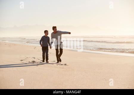 Father And Son Walking Along Winter Beach Hand In Hand