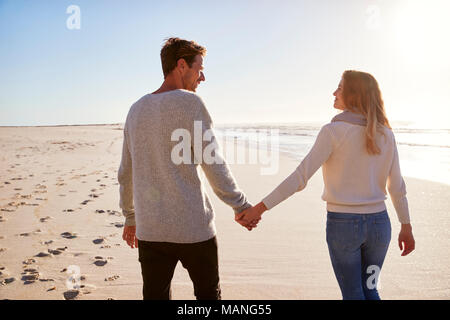 Rear View Of Loving Couple Walking Along Winter Beach Together Stock Photo