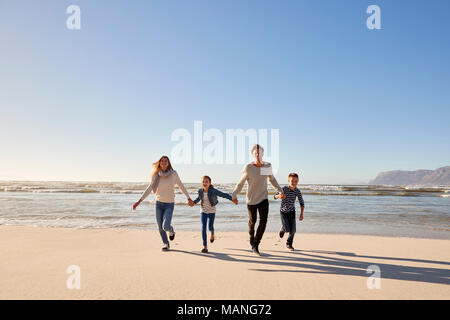 Family On Winter Beach Holding Hands And Running Towards Camera