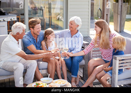 Multi Generation Family Enjoy Outdoor Drinks And Snacks At Home Stock Photo