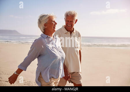 Senior Retired Couple Walking Along Beach Hand In Hand Together Stock Photo
