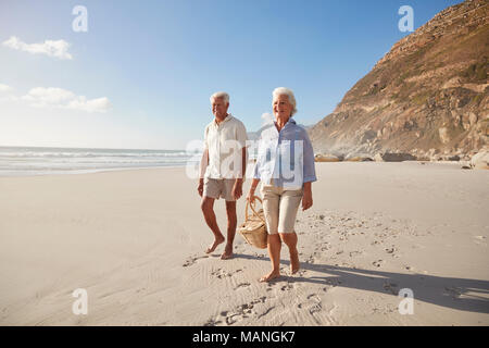 Senior Retired Couple Walking Along Beach Hand In Hand Together Stock Photo