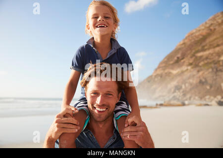 Portrait Of Father Carrying Son On Shoulders On Beach Vacation
