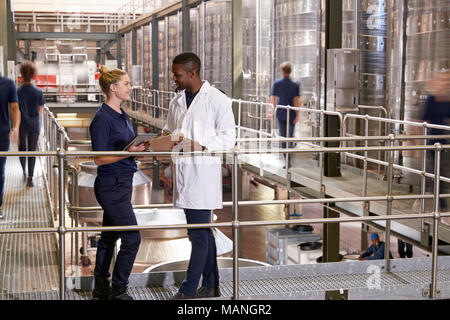 Two staff talking in a modern winemaking factory, close up Stock Photo