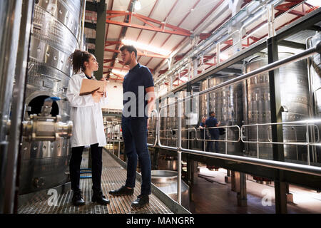 A male and a female technician talking at a wine factory Stock Photo