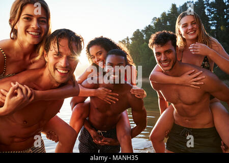 Three young adult couples piggy backing in a lake, close up Stock Photo