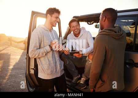 Three male friends on a road trip using a tablet computer Stock Photo