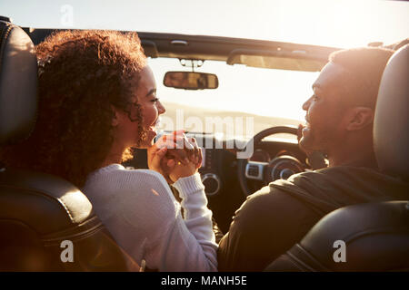 Couple driving look at each other, hold hands, passenger POV Stock Photo