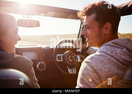 Happy couple driving in car with sunroof open, passenger POV Stock Photo