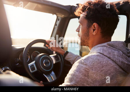 Side view of young Hispanic man driving with sunroof open Stock Photo