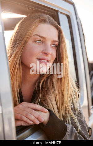 Young white woman looking away through open window of a car Stock Photo