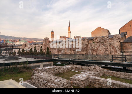 SARAJEVO, BOSNIA - JAN 25 2018: Historical Taslihan ruins with the old watch tower and minaret of Gazi Husrev mosque at the background. Ruins are a next to Sarajevo Europe Hotel. Stock Photo