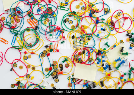 Colourful paper clips, elastic rubber bands, drawing pins thumb tacks and sticky notes as a texture background. Office concept. Stock Photo