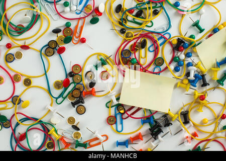 Colourful paper clips, elastic rubber bands, drawing pins thumb tacks and sticky notes as a texture background. Office concept. Stock Photo