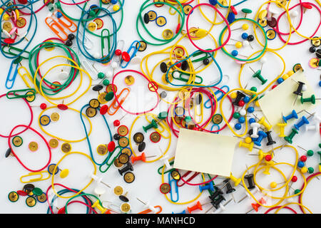 Colourful paper clips, elastic rubber bands, drawing pins thumb tacks as a texture background. Office concept. Stock Photo