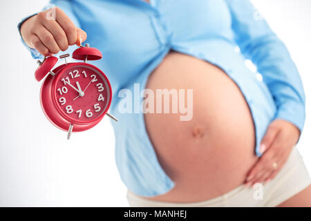 Counting hours expecting child birth. Motherhood concept. Pregnant woman holding alarm clock, studio shot. Stock Photo