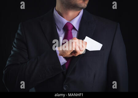 Businessman in elegant suit and with a tie, shows business card with copy space, studio shot Stock Photo