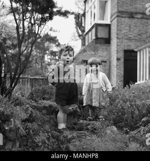1960s, historical, a young boy and girl standing on some steps by a back garden rockery outside, England, UK. Stock Photo