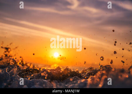 Sunrise light shining on ocean wave with orange tones Stock Photo