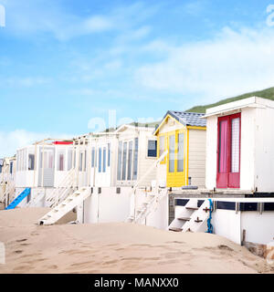 Beautiful painted beach huts or small houses onto a beach. Beach dunes and sand, beach life or summer holidays scene. Stock Photo
