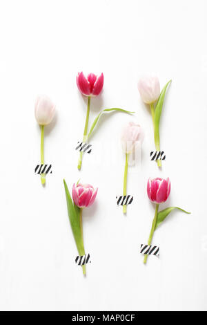 Styled stock photo. Feminine Easter, spring composition with pink tulips taped on white background. Floral pattern. Flat lay, top view, vertical pictu Stock Photo