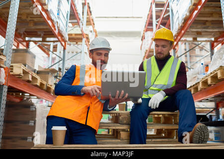 Two Workers using Laptop in Warehouse Stock Photo