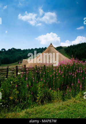 Newly-thatched roof & porch of the Great Roundhouse (dismantled 2006) within a ditched & fenced enclosure at Butser Ancient farm, Hampshire, UK. Stock Photo