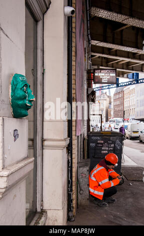 Worker in hi visibility jacket crouching by wall near Borough Market, Southwark, London, England, UK Stock Photo