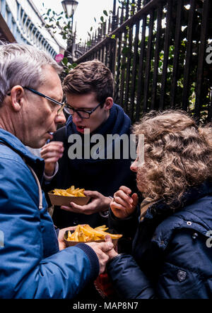 Three people eating chips, London, England, UK Stock Photo