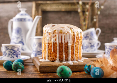 Fresh Russian cake and dyed quail eggs on a wooden background. With an ancient frame in the background. A table served for Easter. Stock Photo