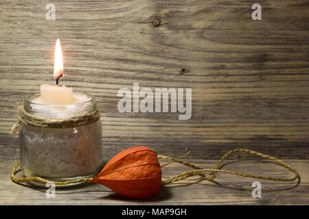 Burning white candle in glass jar on wooden background Stock Photo