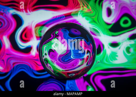 clear glass ball with coloured patterns of light reflected in it. Stock Photo