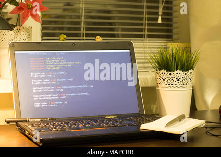 Web developer's workplace. Laptop with a blocknote and a metal pen. Digital technology modern background. Stock Photo