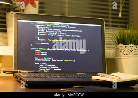 Web developer's workplace. Laptop with a blocknote and a metal pen. Digital technology modern background. Stock Photo