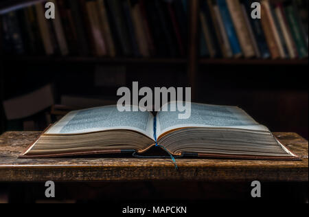 old open book on a wooden table in a dark librarian Stock Photo