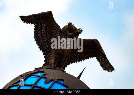 metal owl with world globe against the blue sky. Stock Photo