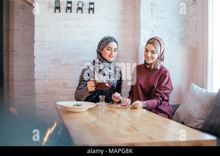 two caucasian muslim woman drinking tea in cafe Stock Photo