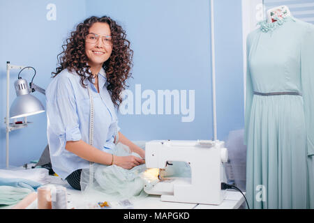 cherrful seamstress sitting on the desk with scissors indoors Stock Photo