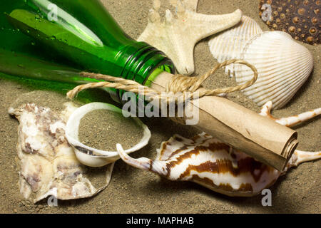 Message in a bottle. A roll of paper in a bottle on the sand. Sea shells. Stock Photo