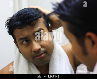 indian asian man looking after his appearance in front of a mirror beauty styling lifestyle.hair styling Stock Photo