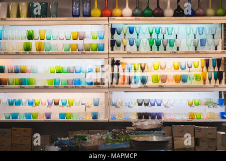Shelves with multi-colored glasses at dishes shop in Chatuchak weekend market. Chatuchak market is a famous shopping area in Bangkok Stock Photo