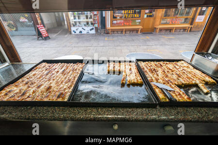Famous Bosnian pastry borek bourek with spinach, chease and minced meat in a bourek house cade showcase. Bourek is a most famous breakfast dish. Stock Photo