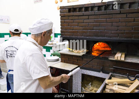 Man cooking traditional Italian pizza in a wood-fired oven at L'Antica Pizzeria Da Michele, Naples, Italy Stock Photo