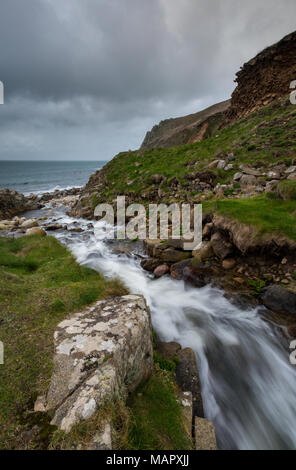 A stream or waterfall tumbling or running through the hillside down to the beach in the cot valley at porth nanven in west cornwall neat st just. Stock Photo