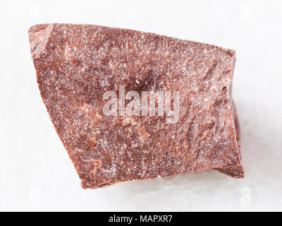 macro shooting of natural mineral rock specimen - piece of raw red marble stone on white marble background Stock Photo