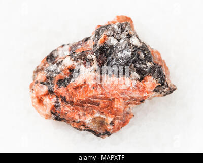 macro shooting of natural mineral rock specimen - raw red granite stone on white marble background Stock Photo